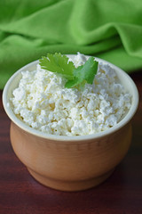 Fresh homemade cottage cheese in a clay plate on a wooden background.Healthy diet.