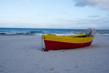 A small yellow fishing boat left on the sandy beach