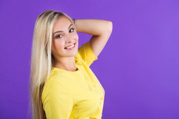 beautiful young woman in a yellow dress on a purple background with her hair