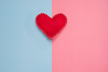 Handmade red heart on a pink and blue background with copy space. Background minimalism for Valentine's Day, Mother's Day, Birth of a child.