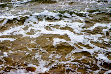sea shore or tide waves moving in coast with foam over sand as texture