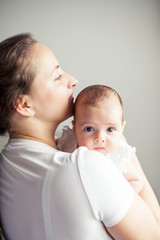 Young beautiful mother holds a baby. Mom kisses her baby. Children's bedroom.