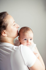 Young beautiful mother holds a baby. Mom kisses her baby. Children's bedroom.