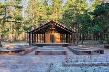 Wooden house stage for free musicians open air performances in pine forest in sunlight, in front of...