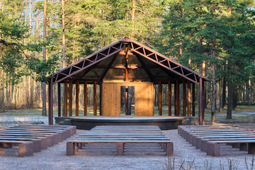 Wooden house stage for free musicians open air performances in pine forest in sunlight, in front of...