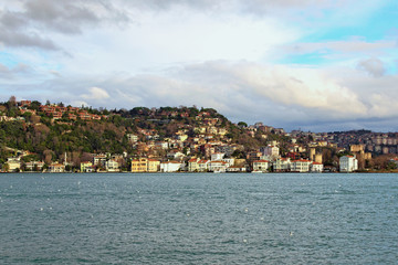 Fototapeta premium Picturesque landscape view of residential buildings on the hill near The Bosporus (Bosphorus or Strait of Istanbul). Clouds over the city. Winter day in Istanbul, Turkey