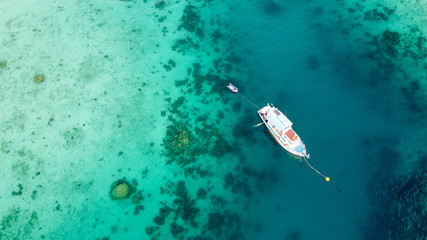 Boat anchored on the coral reef, aerial view from drone