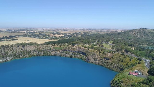 Slow aerial rise over Blue Lake revealing scenic countryside. Mount Gambier, South Australia