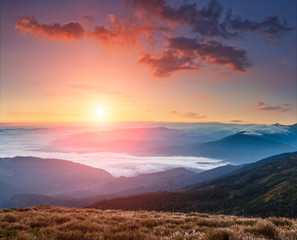 Landscape of colorful sunrise in the mountains. View on foggy hills covered by forest. Concept of the awakening wildlife.