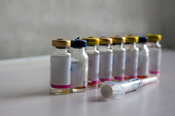 Antibiotic bottles are on a white table with a syringe.
