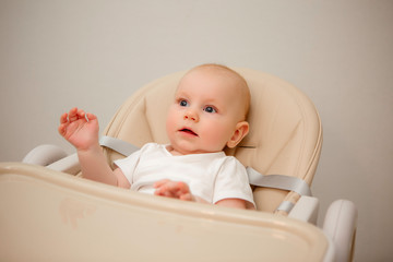 baby 5 months sitting in a high chair smiling