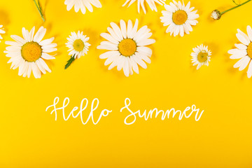 Floral camomile pattern with Hello Summer slogan on bright yellow background, top view, flat lay