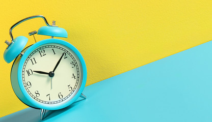 Alarm clock on turquoise yellow background.