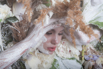 Female portrait in fairy tale stylisation surrounded with natural plants and flowers.