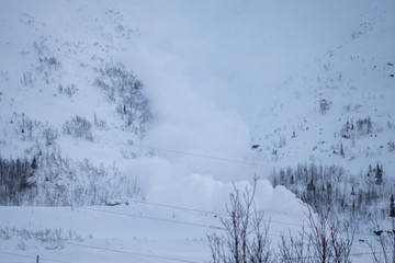 An avalanche descends in the snowy mountains beyond the Arctic Circle