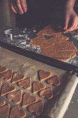 girl preparing cookies in the shape of a heart for the holiday Valentine's Day at home, in a small bakery, family business, authentic, hobby, mood, cozy. Care and love