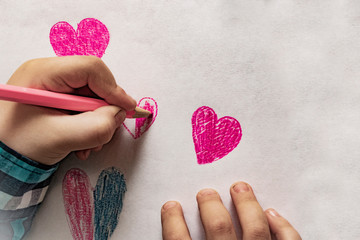  A red heart expressing the child's love, child's hands, sketch book & pencil/pen. Child drawing a heart for Fathers Day or Valentines Day or Mother's Day.