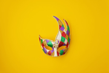 Festive, colorful mardi gras or carnivale mask and accessories over yellow background. Party...