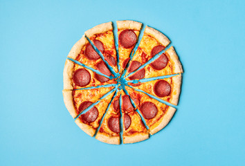 Sliced pizza pepperoni on blue background. Pizza salami slices