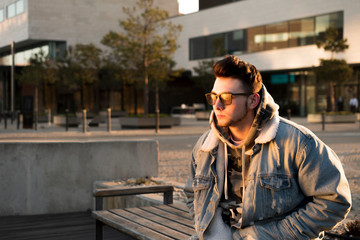 Fototapeta premium Young man rap singer on a street at morning. Man wears sunglass. Hip Hop retro fashion. 