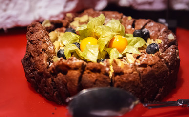 Selective Focused Freshly Baked Homemade Delicious Chocolate Brownie Cake decorated with fresh cape gooseberry and berry fruit. Food Catering, Healthy Dessert, Sweet, Treat, Cooking and Hobby concept