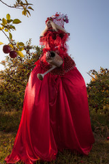 Obraz na płótnie Canvas Sensual blond girl in fantasy red fairy tale stylization in apple park.