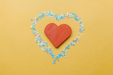 Red  wooden heart  on yellow background with circuits of flowers