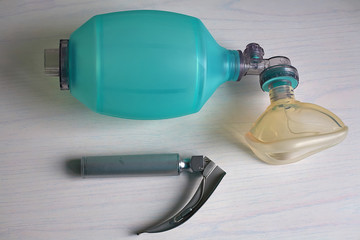 An Ambu bag with a laryngoscope is located on a white table.