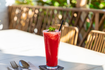 Glass with red cocktail with paper black pipe on table against blurred background
