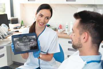 Female dentist showing teeth x-ray on tablet