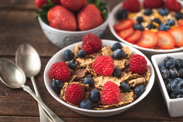 Granola chips with blueberries and raspberries in white bowl.