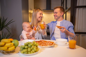 Young family with a baby eating sitting at the table