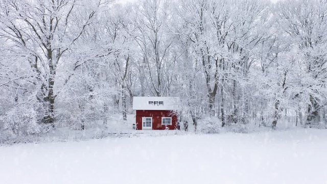 Snow falling outside picturesque red cabin in the forest