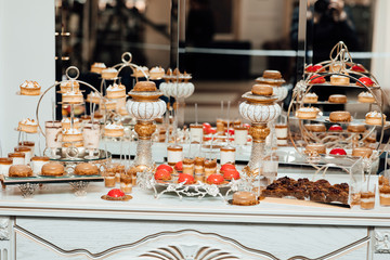 Candy bar. Table with sweets, candies, dessert. Candy Bar. Sweet holiday buffet with cupcakes and other desserts. Delicious wedding reception candy bar. Delicious and tasty dessert table