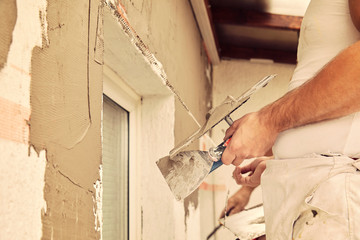 Construction workers plaster a wall.
