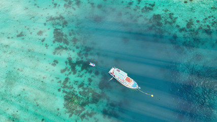 Fototapeta premium Boat anchored on the coral reef, aerial view from drone