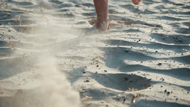 Legs of a man in close form, running barefoot on the hot sand near the sea, in slow motion. Summer sports run on the beach. Healthy lifestyle. Sporty legs exercising on a runner beach working out.