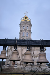 Bronze bells hang in a row against the background of the church.