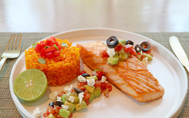 Closeup grilled salmon steak with Mediterranean salsa and saffron rice