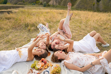 View from above. The company of beautiful girlfriends have fun and enjoy a picnic outdoors