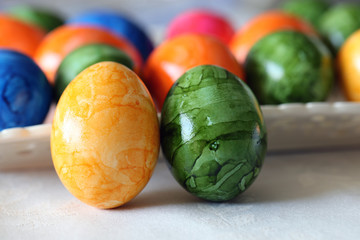 Colorful and joyful Easter decorations on a table. Closeup color image of multiple painted Easter eggs with happy and vibrant colors including blue, green, orange, yellow and pink. Shiny marbled color