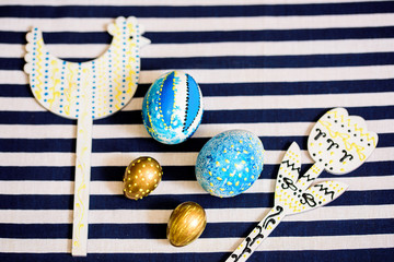 blue easter eggs on a yellow background. blue striped napkin. Easter concept. copy space. Flat lay, top view, trendy modern celebration style, close-up.