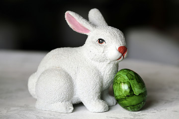 Colorful and joyful Easter decorations on a table. Closeup color image of one ceramic white Easter bunny figure and colorful painted Easter eggs with shiny marbled surface. Happy and vibrant colors.