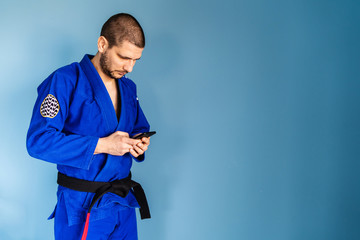 Brazilian jiu jitsu bjj caucasian athlete instructor standing in front of the blue wall wearing...