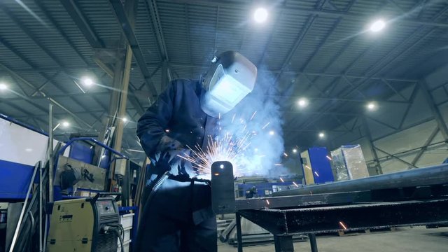Professional Heavy Industry Welder working at welding factory. Factory worker is using a cutting tool to weld metal