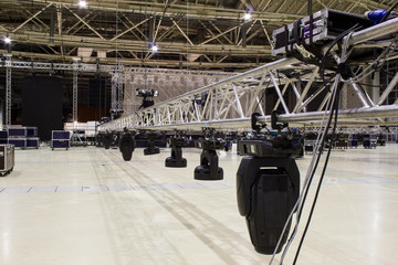 Installation of professional sound, light, video and stage equipment for a concert. Stage lighting equipment is clamped on a truss for lifting.