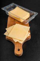 Slices of yellow cheese in a plastic package. Food from the market on the kitchen table.