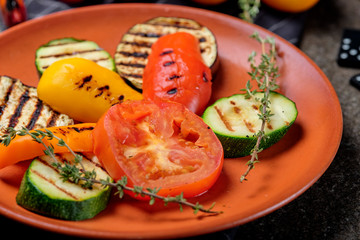 Top view delicious grilled vegetables with vegetables and spices on black stone background. Barbecued healthy food.