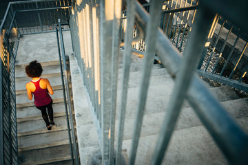 Woman in fitness attire running stairs in urban setting