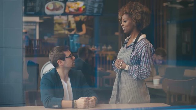 Cheerful young waitress taking orders from male customer